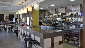 Een bar met een toog, flessenrekken en zitplaatsen.