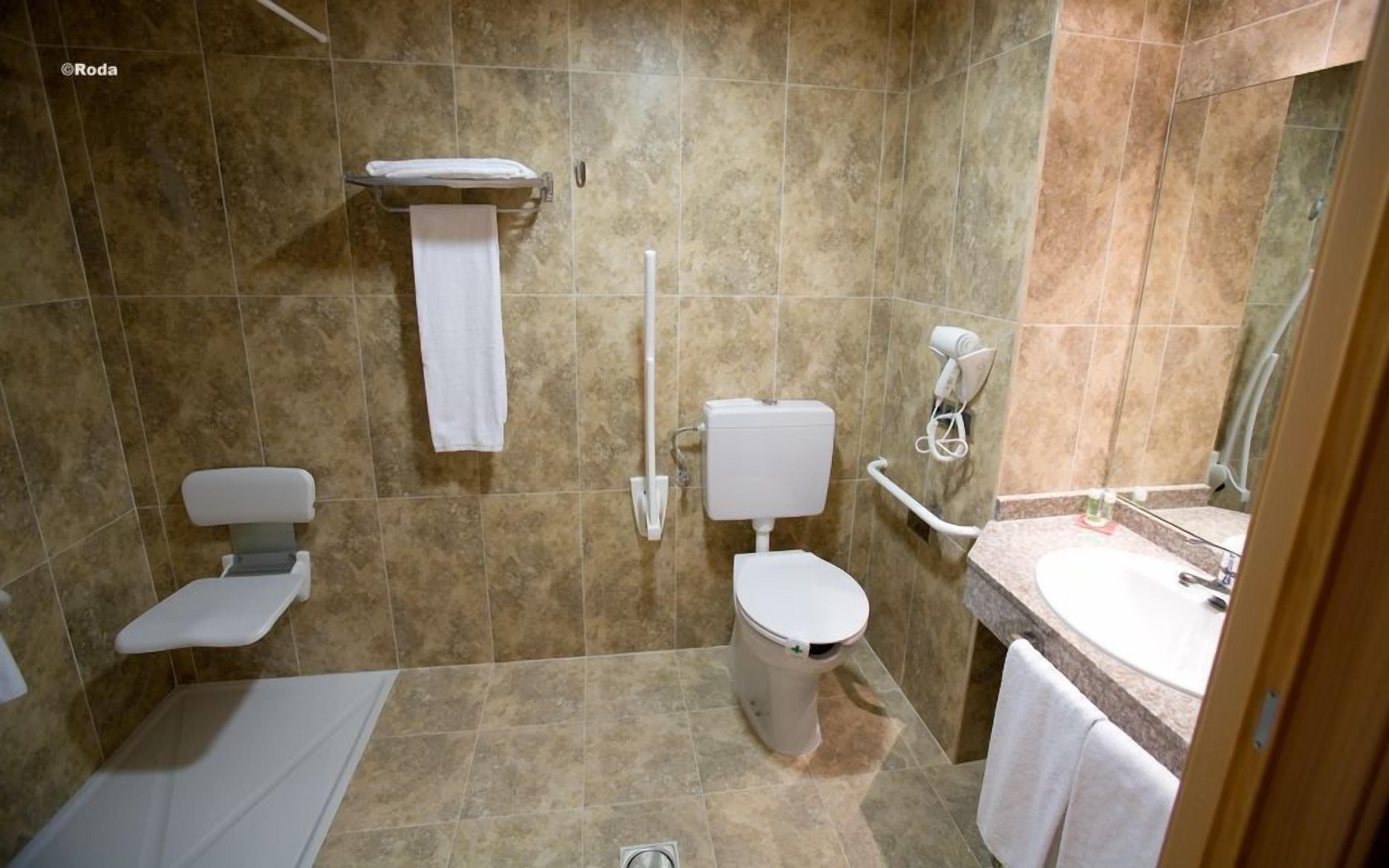 Un bany amb vàter, bidet i banyera, amb elements blancs.