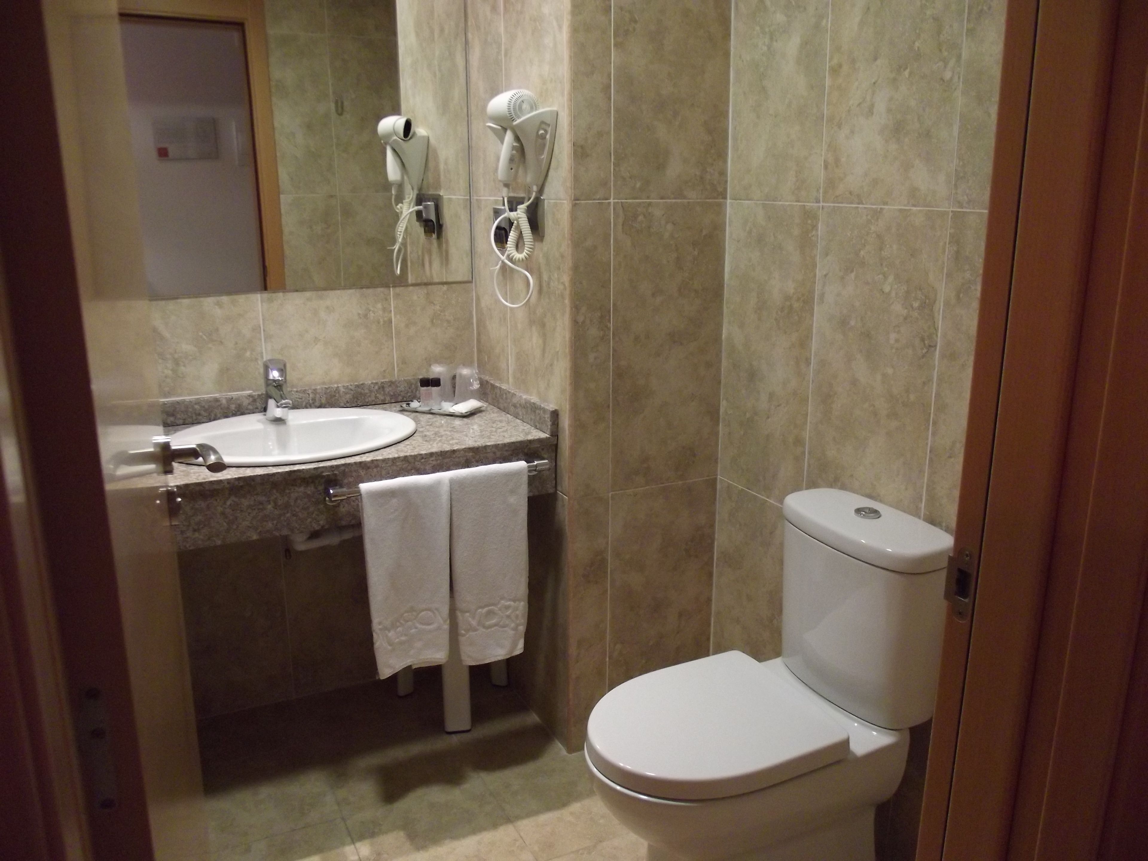 A bathroom with a sink, mirror, towel rack, and toilet.
