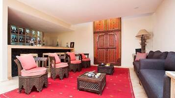 Una sala de estar con alfombra roja, muebles de madera, un sofá, una mesa de centro y una estantería.