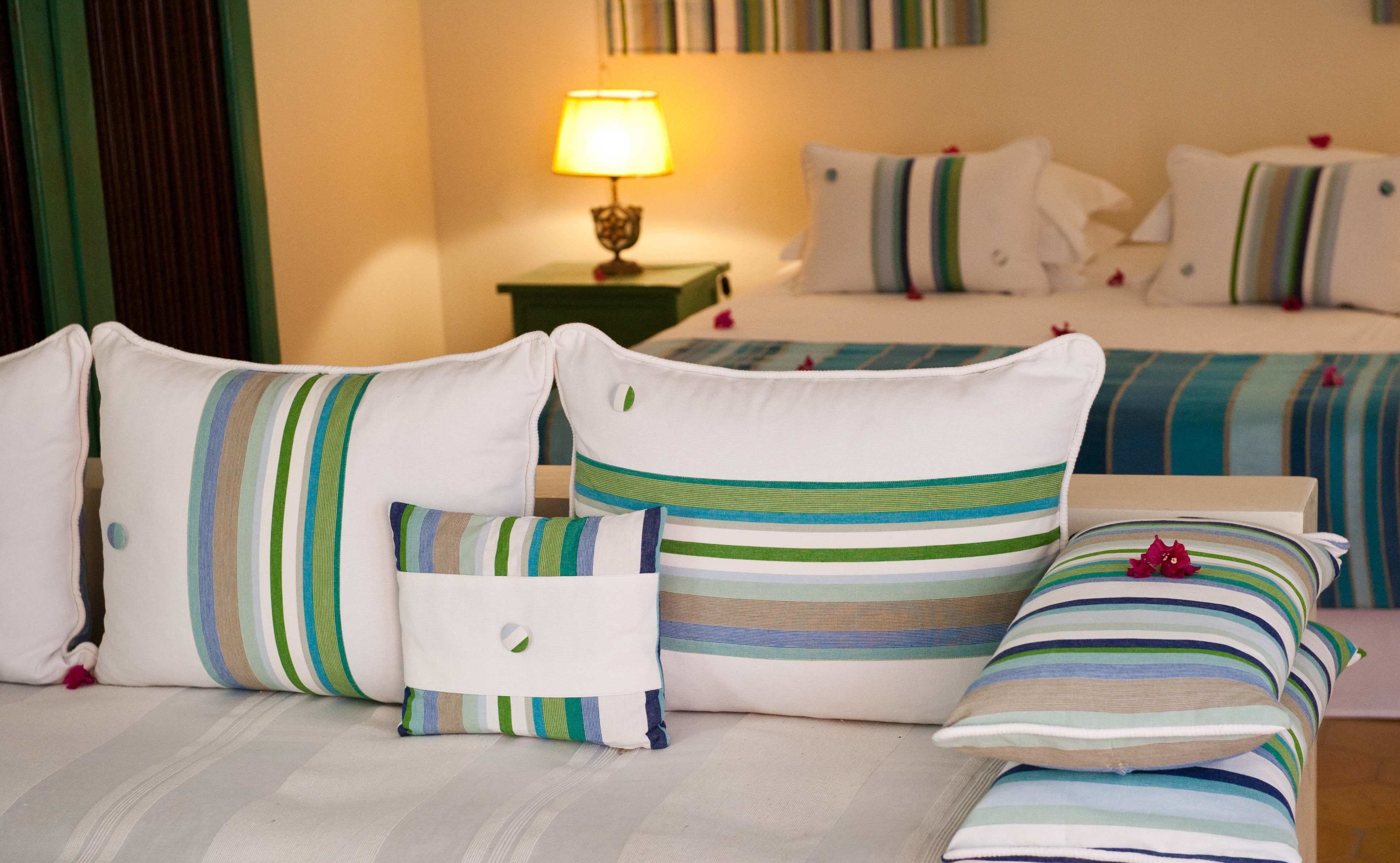 Una habitación de hotel con cama, almohadas y una mesita de noche con lámpara.