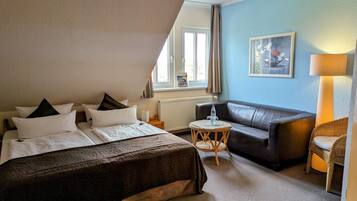 A bedroom with a bed, a sofa, a small round table, and a lamp.