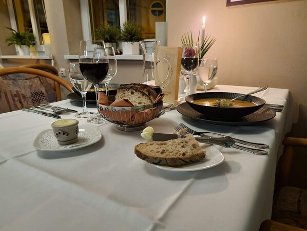 A dining table set with bread, soup, wine glasses, and a candle. - KURHOTEL Bad Suderode (Quedlinburg)