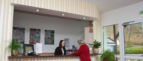 A reception desk with a striped wall, a receptionist, and a guest.