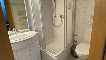 A modern bathroom with a glass-enclosed shower, a sink, and a toilet.