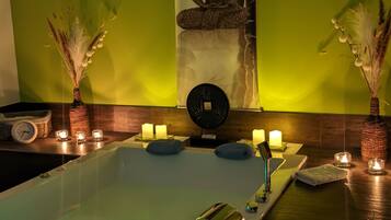 A spa area with a large bathtub, candles, and a Buddha statue.
