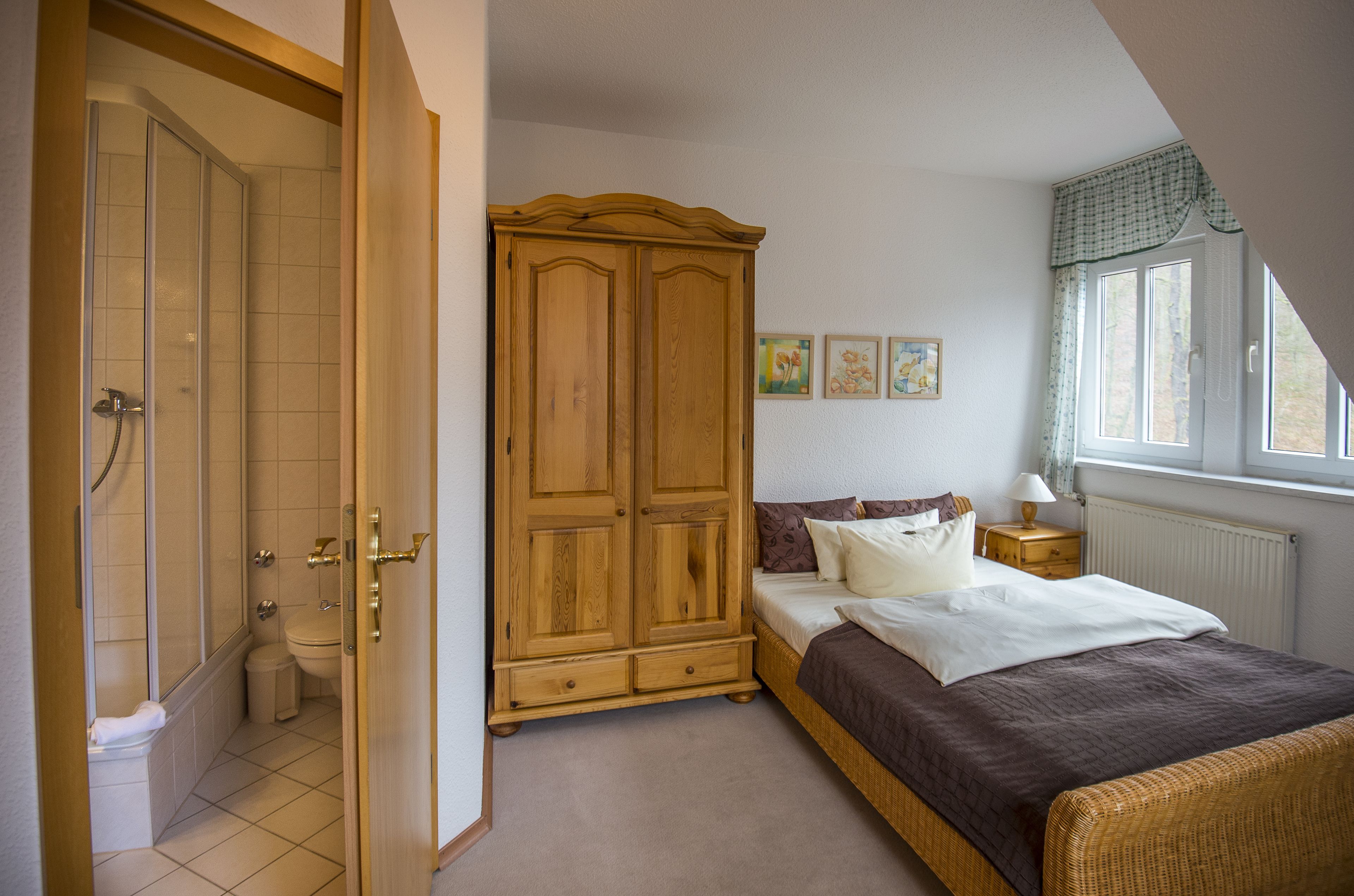 A bedroom with a bed, wardrobe, and a window.