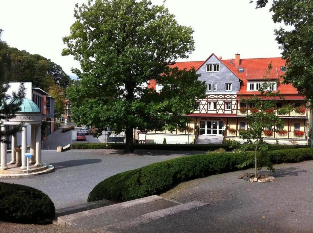 A traditional building with a red roof, a balcony with flower boxes, and a well-maintained garden area.