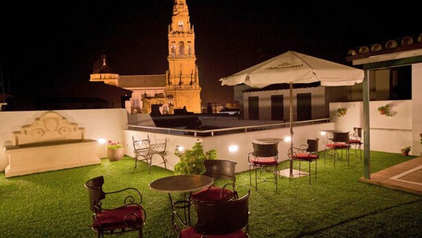 An outdoor patio with a fountain, seating, and a view of a historic tower at night. -  Hotel Bestprice Córdoba (Córdoba)