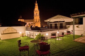 An outdoor patio with a fountain, seating, and a view of a historic tower at night. -  Hotel Bestprice Córdoba (Córdoba)