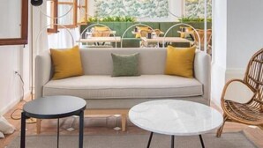 A modern living room with a sofa, two round tables, and a wicker chair. -  Hotel Bestprice Córdoba (Córdoba)