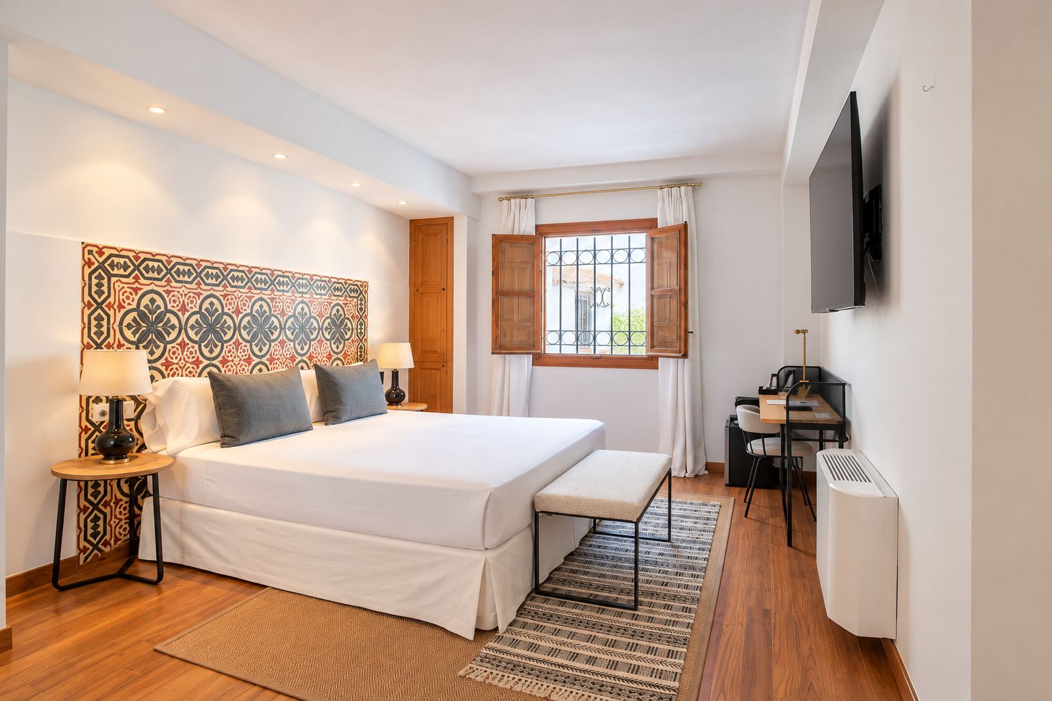 Een hotelkamer met een groot bed, een bureau, een stoel, een televisie en een raam met gordijnen.