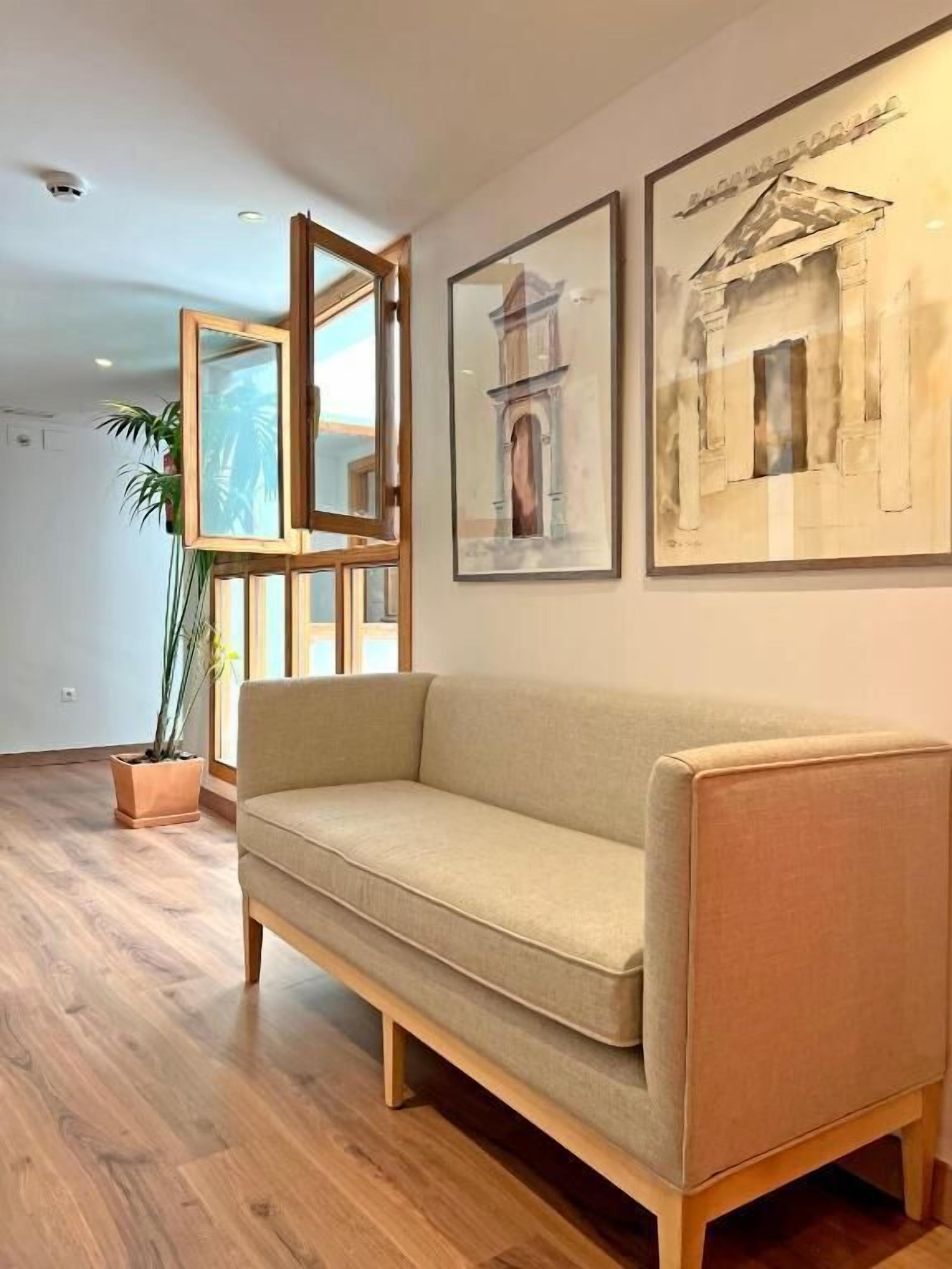 Een moderne woonkamer met een beige bank, houten vloer en een lijstwerk met kunst aan de muur.