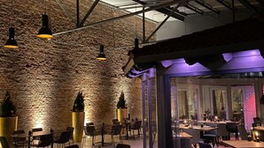 An indoor dining area with brick walls, hanging pendant lights, and tables and chairs arranged for guests. - Hotel Alte Redaktion Superior (Gevelsberg)