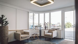 A modern interior with two armchairs, a large potted plant, a vase with flowers, and a geometric ceiling light. - Hotel Alte Redaktion Superior (Gevelsberg)