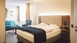 A hotel room with a bed, a small table, a chair, a TV, and a window with curtains. - Hotel Alte Redaktion Superior (Gevelsberg)
