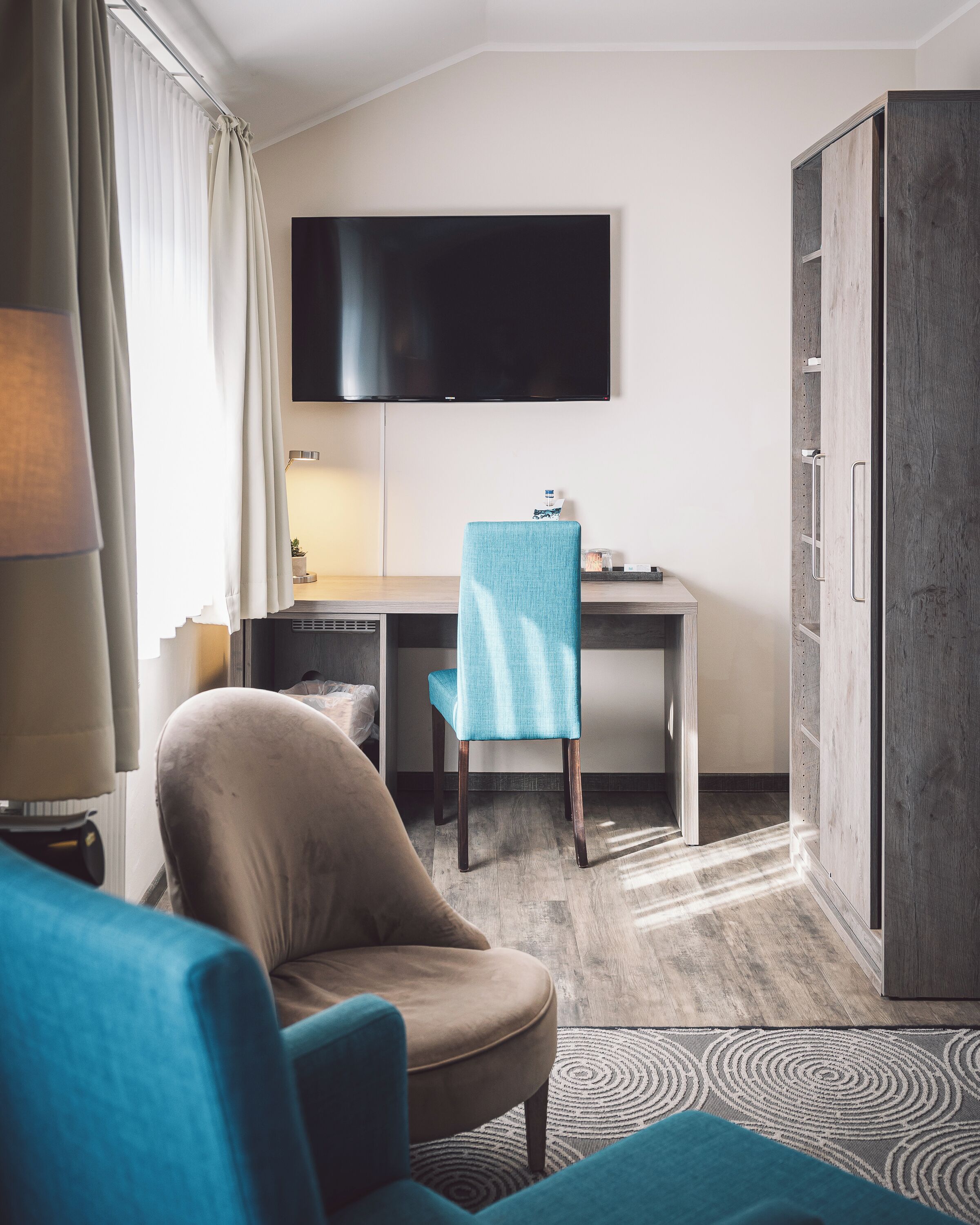 Ein Hotelzimmer mit Bett, Schreibtisch, Fernseher, Sessel und Kleiderschrank.