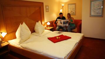 Quarto de hotel com uma cama grande, duas luminárias de cabeceira, uma cabeceira de madeira e um cobertor vermelho.