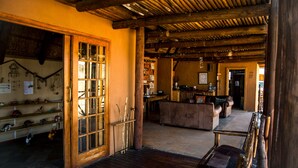 A rustic interior with wooden beams, a wooden door with glass panels, and a seating area with a bench and a sofa. - Xaus Lodge (Mier)