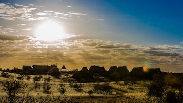 Traditional huts sit atop a gentle elevation, offering a serene view of the surrounding landscape.