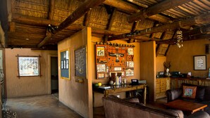 A rustic interior with a wooden ceiling, a leather sofa, a wooden table, and a bulletin board with various pictures and notes. - Xaus Lodge (Mier)