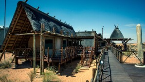 A rustic building with a thatched roof, wooden deck, and a conical structure. - Xaus Lodge (Mier)