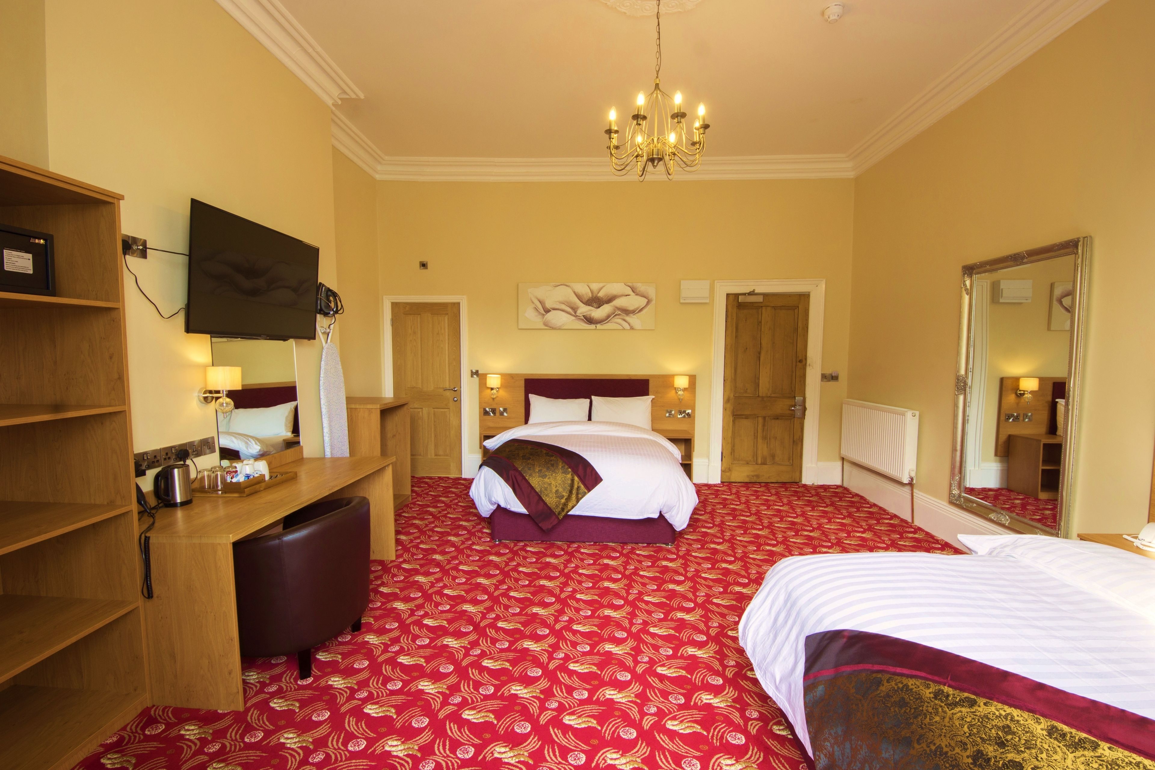 Une chambre d’hôtel avec un grand lit, un bureau avec une chaise, une télévision et un miroir.