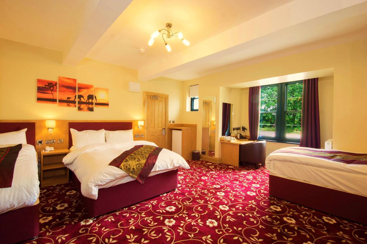 Habitación de hotel con dos camas, un espejo grande, un escritorio y una ventana con cortinas.