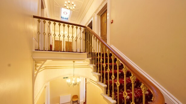 A grand staircase with ornate railings and a red carpeted landing area. - Edgerton Hotel (Huddersfield)