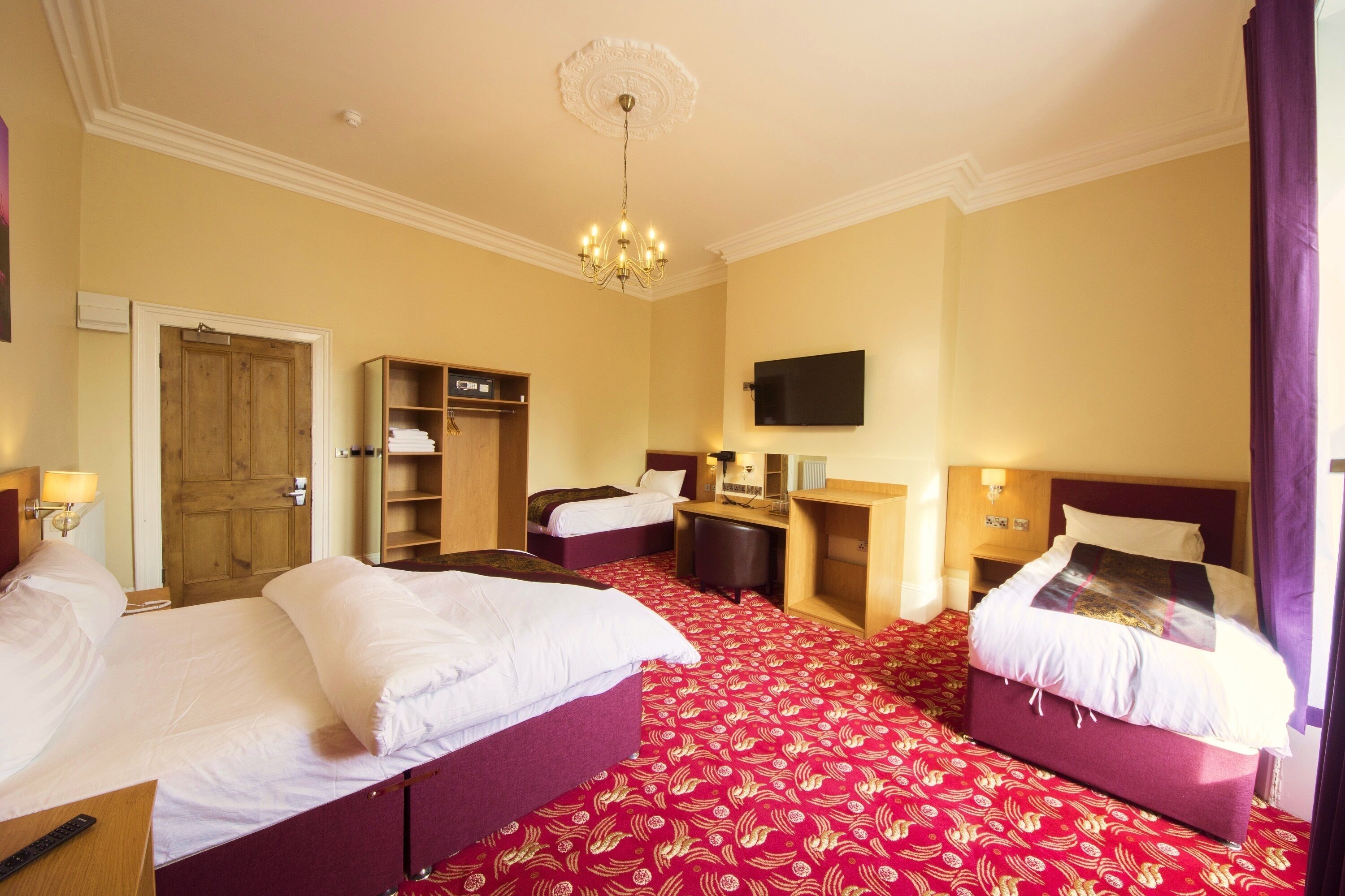 A hotel room with two beds, a desk, a television, and a wardrobe.