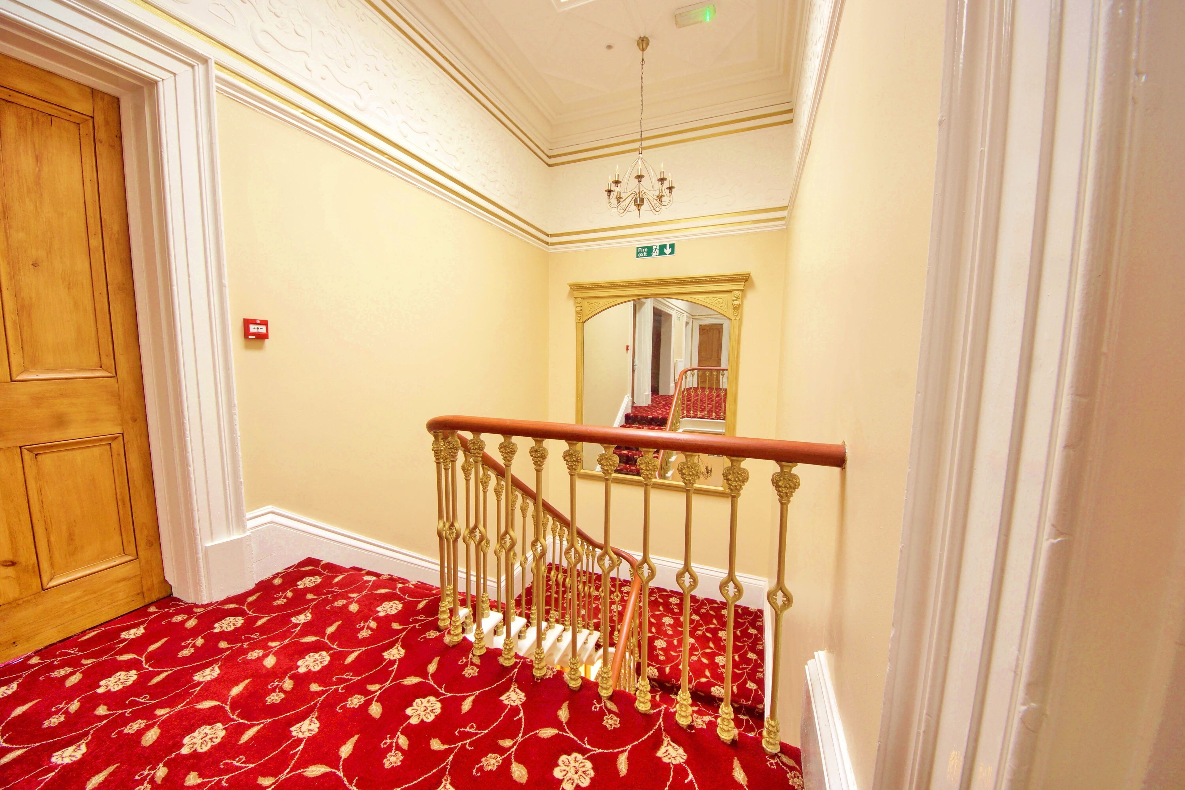 A staircase with ornate railings and a red carpeted floor.