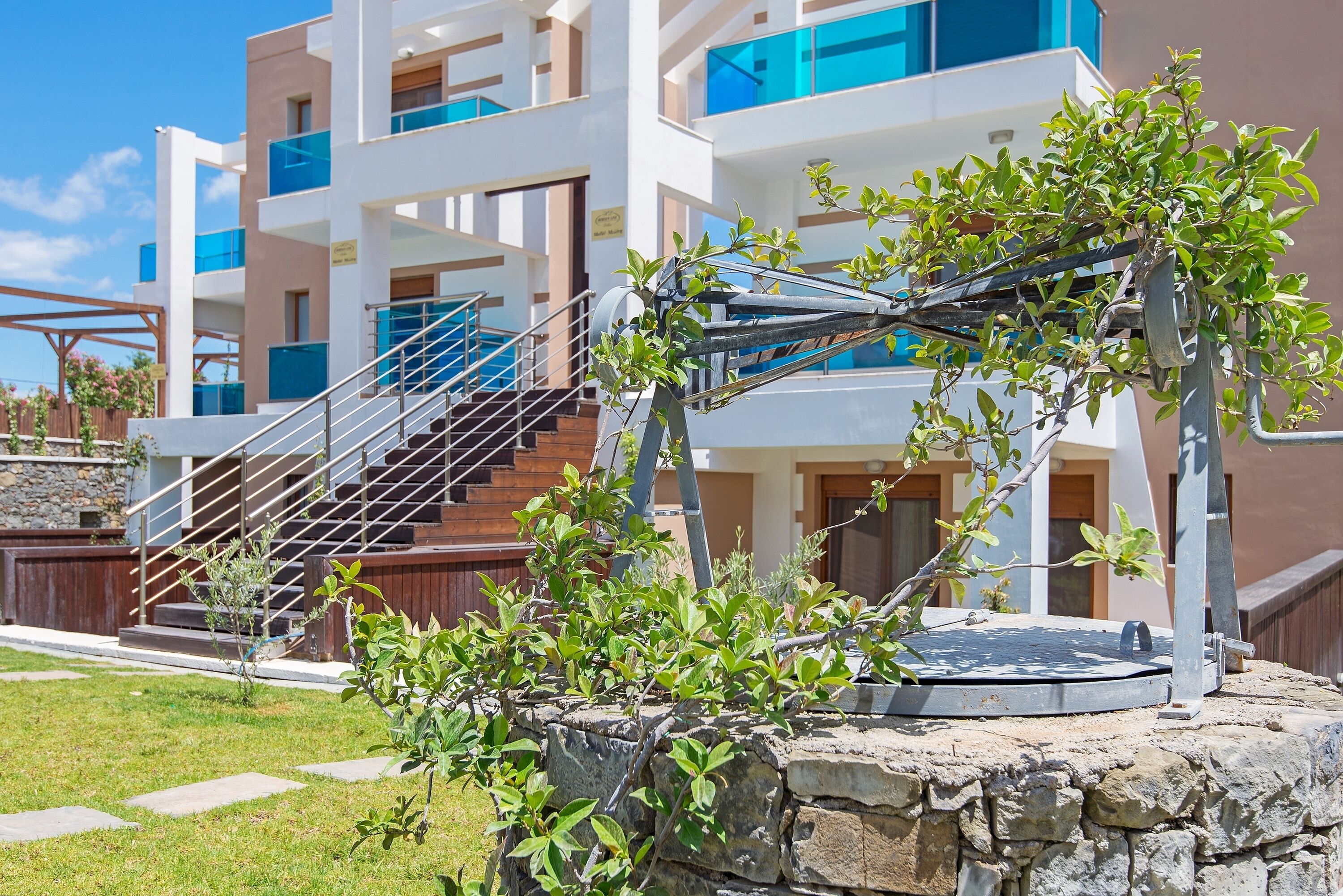 A modern building with a stone staircase leading to a balcony, surrounded by greenery.