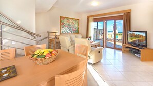 Una sala de estar moderna con comedor, televisor y un balcón con vistas.