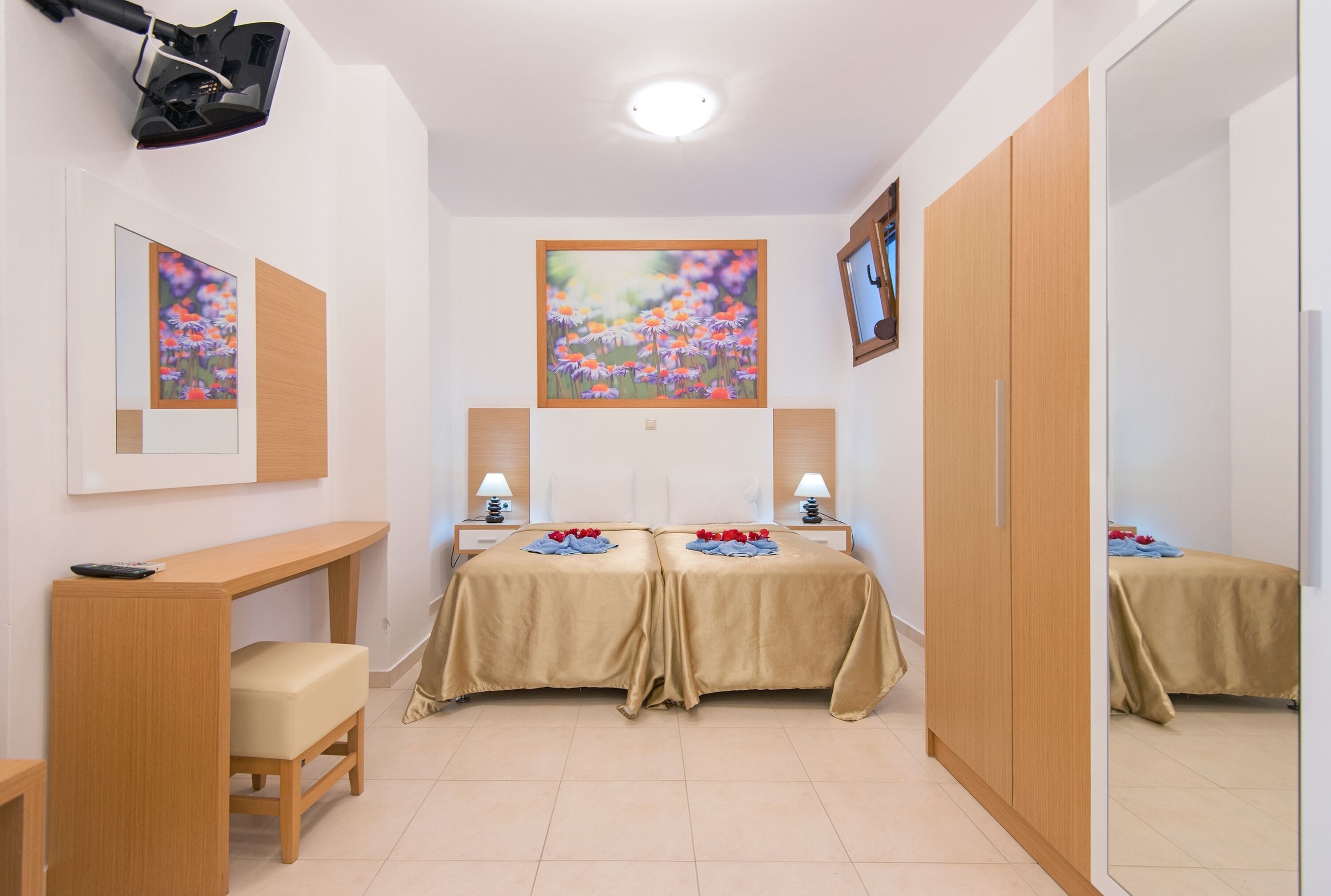 A hotel room with two beds, a desk, a chair, a mirror, and artwork on the walls.
