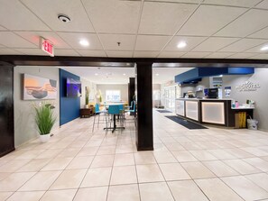 A hotel lobby with a reception desk, a seating area, and a large window. - Microtel Inn & Suites by Wyndham Columbia/At Fort Jackson (Columbia)