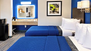 A hotel room with two beds, a desk, a microwave, and a sink.