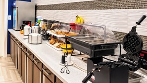 A buffet setup with various food stations, including a waffle maker, and a coffee machine. - Executive Inn & Suites Joaquin (Joaquin)