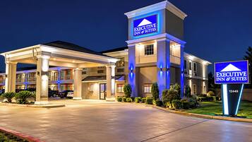 A hotel with a prominent sign reading 'EXECUTIVE INN & SUITES' and a well-lit entrance.