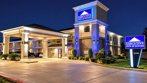 Un hôtel avec une enseigne bien visible indiquant « EXECUTIVE INN & SUITES » et une entrée bien éclairée.