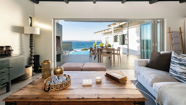 Una sala de estar moderna con vista al mar, una mesa de centro de madera y un sofá.