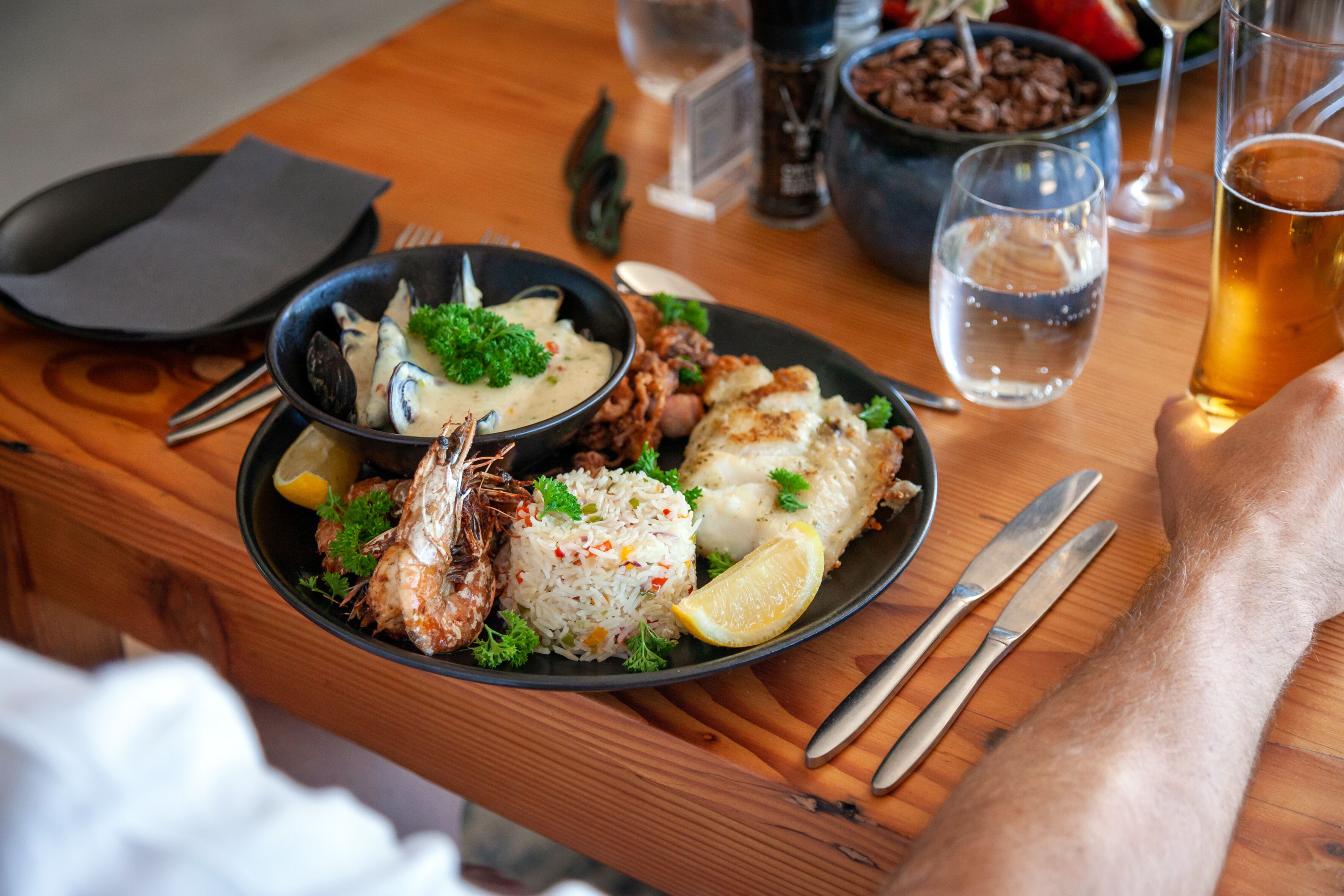 A wooden table with a meal consisting of seafood, rice, and lemon slices.