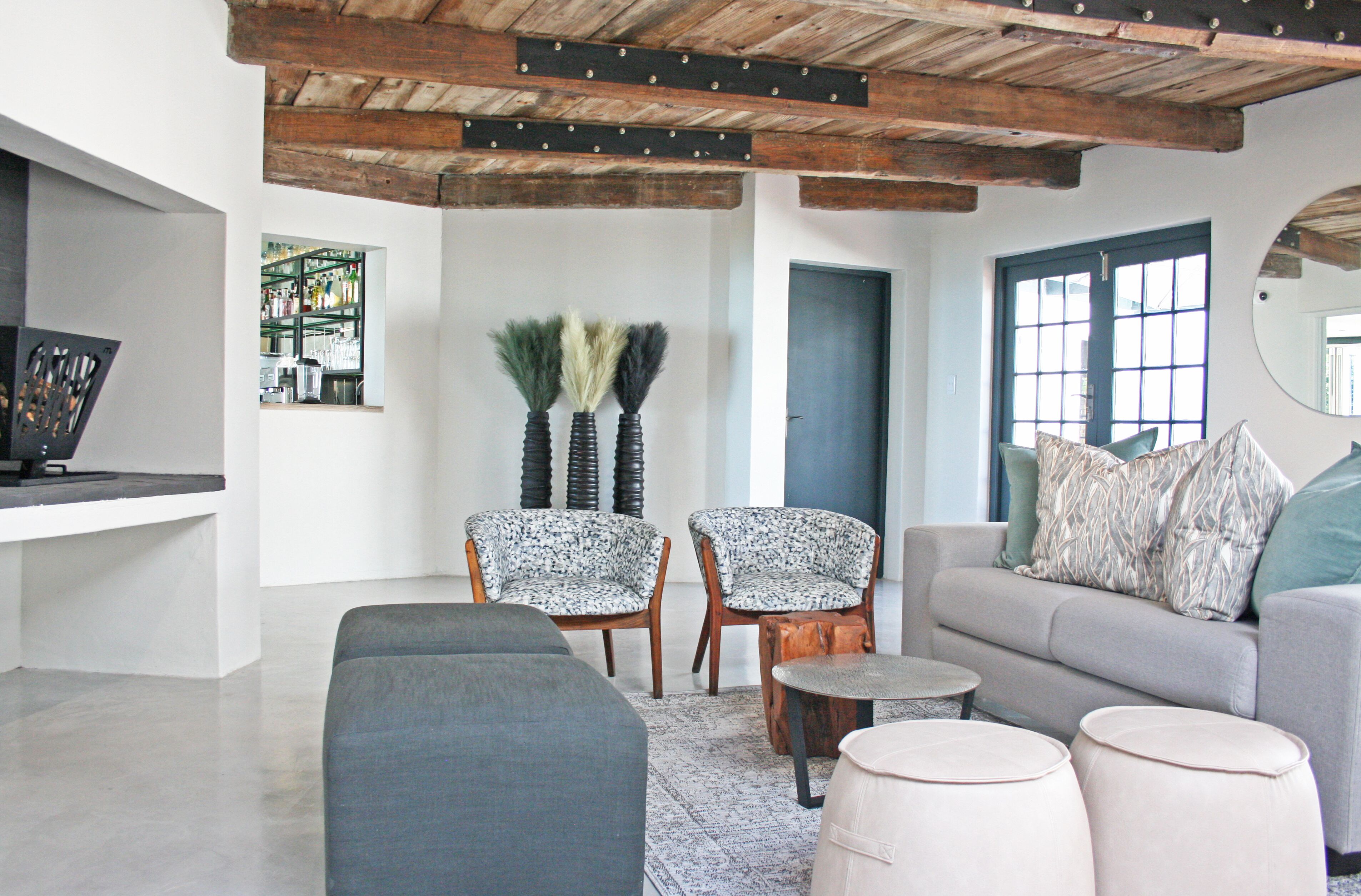 A modern living room with a grey sofa, two patterned armchairs, a coffee table, and a TV.