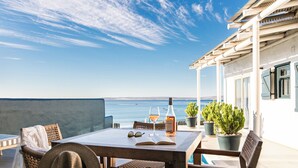 Un espacio al aire libre con mesa, sillas y vista al mar.