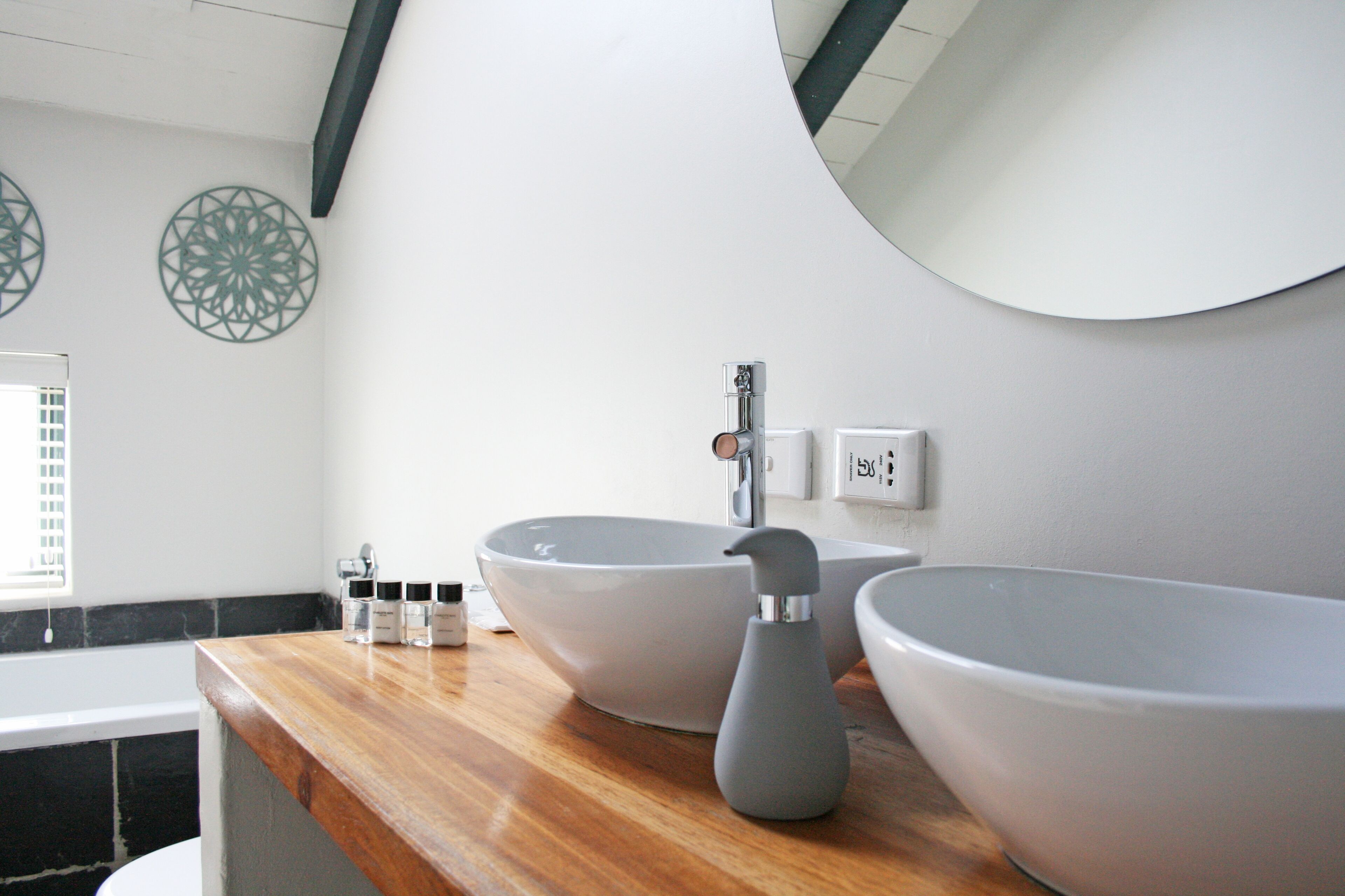 A bathroom with two large white sinks, a wooden countertop, and decorative wall art.