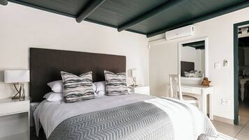Un dormitorio moderno con una cama grande, una mesita de noche, un escritorio y un espejo.