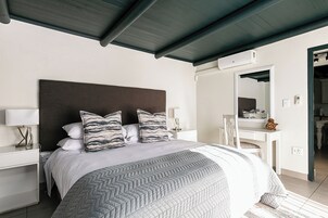Un dormitorio moderno con una cama grande, una mesita de noche, un escritorio y un espejo.
