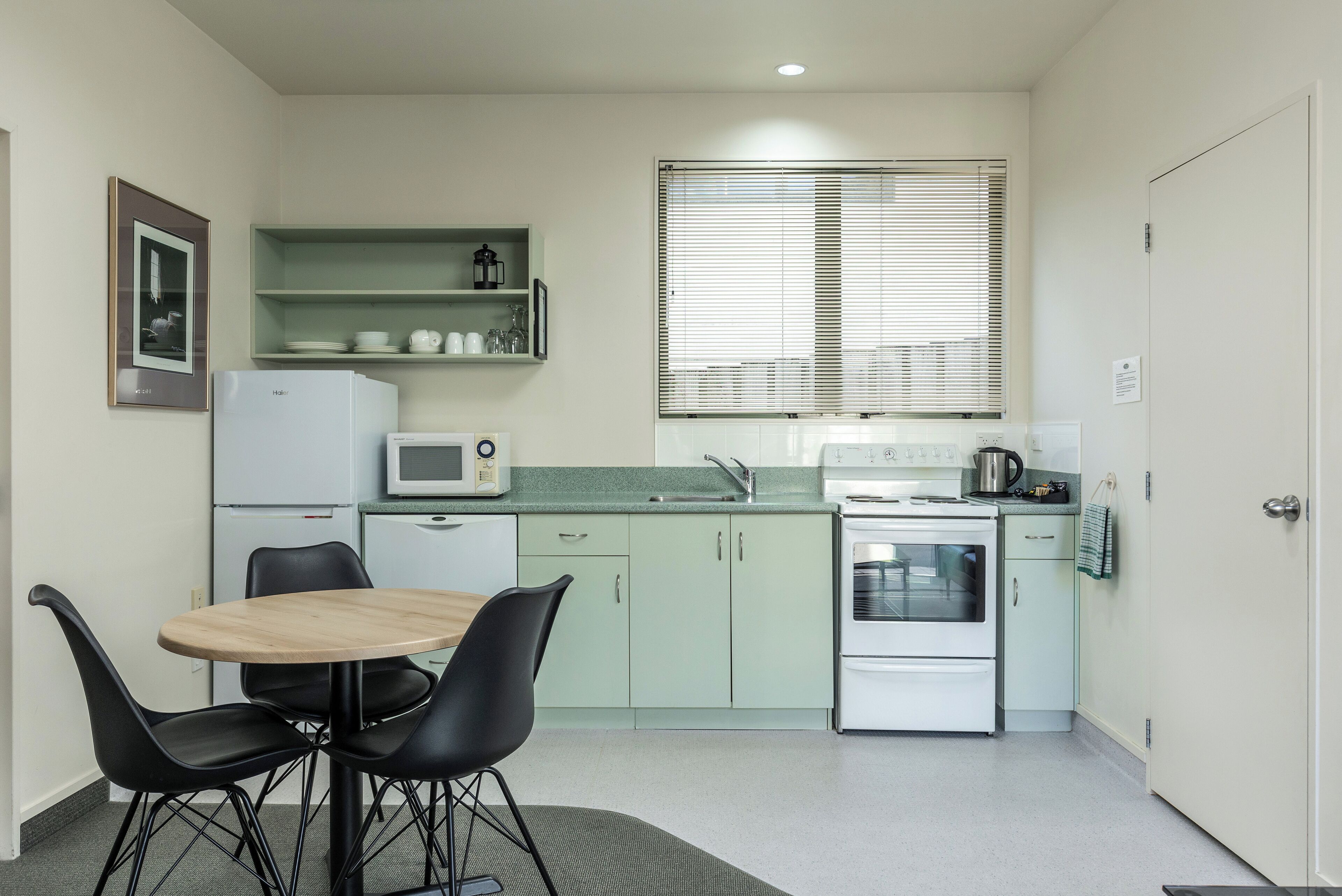 A compact kitchen with a dining area, including a microwave, stove, and a small refrigerator.