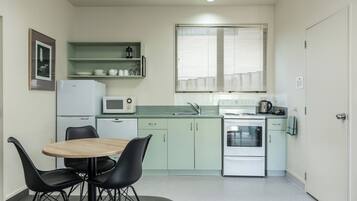 A compact kitchen with a dining area, including a microwave, stove, and a small refrigerator.