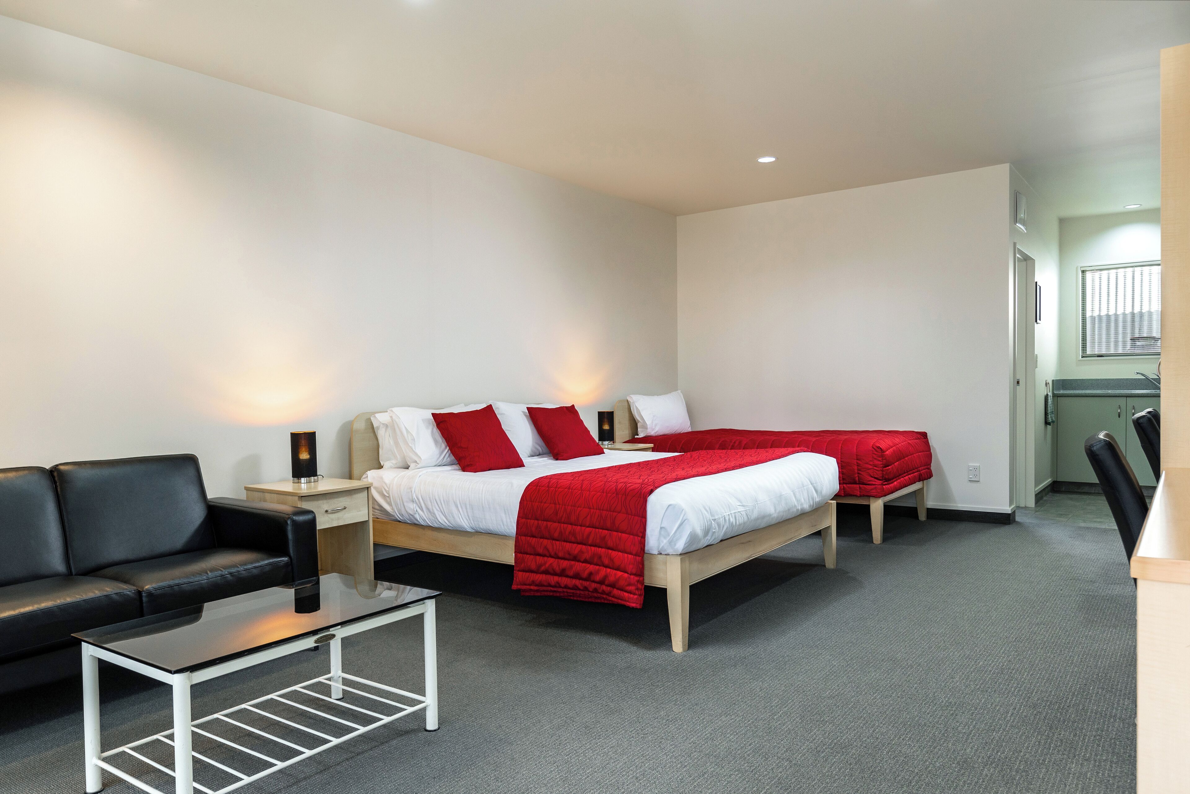 Een hotelkamer met een bed, een slaapbank, een nachtkastje en een klein tafeltje.