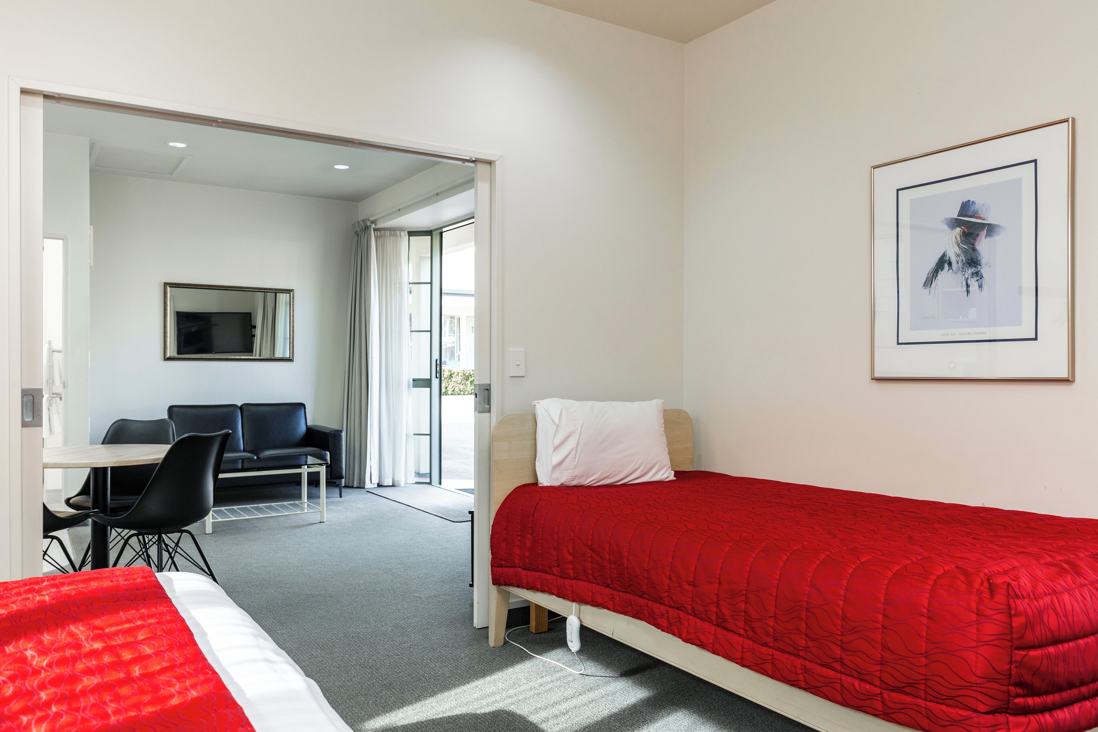 A hotel room with a single bed, a desk with a chair, a sofa, and a large window.